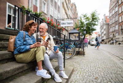 Frau und Mann sitzen auf Treppe und trinken Kaffee in einer Altstadt.