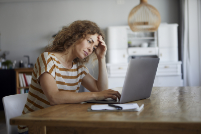 Steigende Mieten müssen schriftlich angekündigt werden. Frau macht sich Gedanken über steigende Miete am Laptop